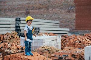 Architect in helmet writing something near new building. little cute boy on the building as an architect photo