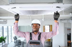 profesional reparador instalando aire acondicionador en un habitación foto