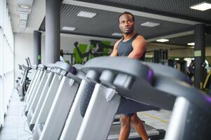 Sportive black man exercising on treadmill in fitness club photo