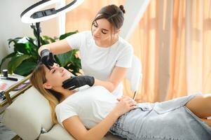 Process of creating permanent brow makeup with a machine at beauty salon photo