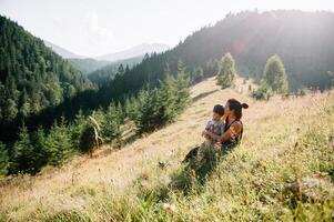 joven mamá con bebé chico de viaje. madre en excursionismo aventuras con niño, familia viaje en montañas. nacional parque. caminata con niños. activo verano vacaciones. ojo de pez lente. foto