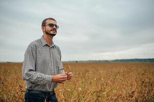 Agronomist holds tablet touch pad computer in the soy field and examining crops before harvesting. Agribusiness concept. agricultural engineer standing in a soy field with a tablet. photo