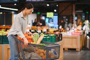 joven mujer comprando vegetales a tienda de comestibles mercado foto