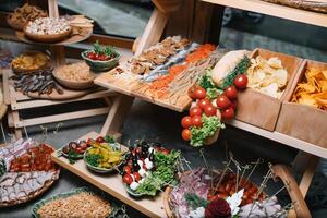 Antipasti board with various cheese and meat snacks with hummus and olives on wooden round board on black table photo