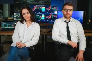 Team of stockbrokers are having a conversation in a dark office with display screens photo