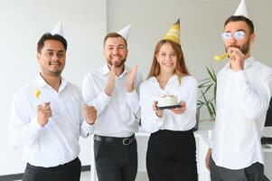 contento mujer de negocios participación cumpleaños pastel mientras haciendo sorpresa fiesta con su colegas en el oficina. foto