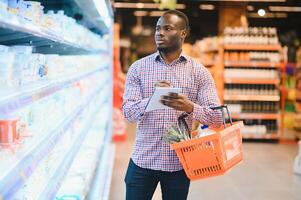 African man shopping at supermarket. Handsome guy holding shopping basket photo