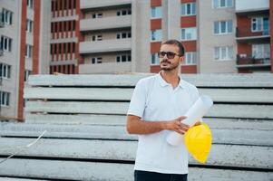 retrato de un arquitecto constructor estudiando diseño plan de el habitaciones, grave civil ingeniero trabajando con documentos en construcción sitio. foto