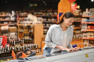 joven sonriente contento mujer 20s en casual ropa compras a supermercado Tienda con tienda de comestibles carro foto