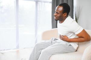 Black Man Having Stomachache Suffering From Painful Abdominal Spasm Standing Touching Aching Abdomen At Home photo