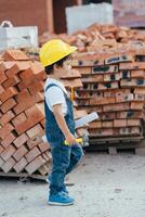 Architect in helmet writing something near new building. little cute boy on the building as an architect photo