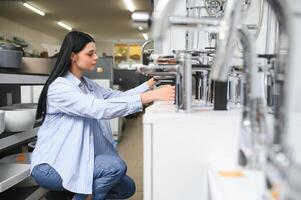 Woman inspects and chooses new kitchen or bath tap faucet at a hardware store photo