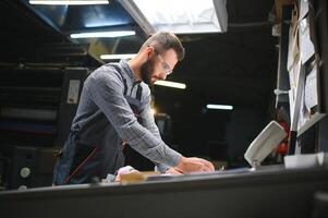 Man working in printing house with paper and paints photo