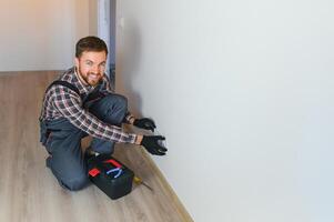 Confident professional electrician in uniform using screwdriver while replacing a socket in apartment after renovation work. photo