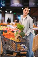 joven mujer comprando vegetales a tienda de comestibles mercado foto