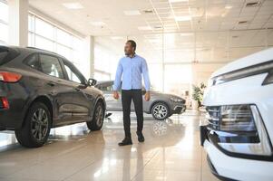 Handsome African man choosing a new car at the dealership photo