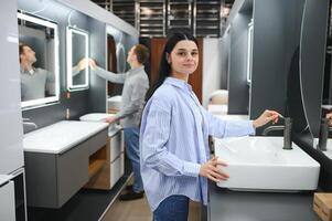 Positive couple choosing wash basin in bathroom furniture shop photo