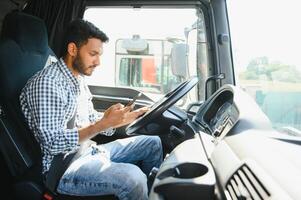 Young handsome indian man using smart phone in his truck. photo