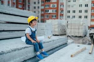 arquitecto en casco escritura alguna cosa cerca nuevo edificio. pequeño linda chico en el edificio como un arquitecto. foto