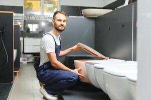 Plumber in uniform at showcase in plumbering store photo