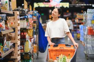 Happy young woman looking at product at grocery store. Smiling woman shopping in supermarket photo