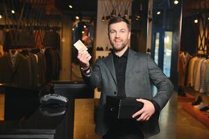 Happy shopper holding boxes of new clothes or shoes and paying with credit card photo