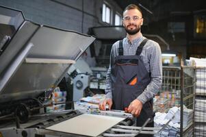 Man working in printing house with paper and paints photo