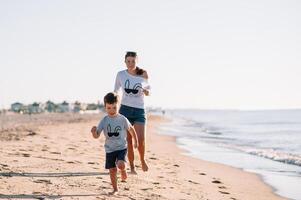 Mother and son playing on the beach at the sunset time. Concept of friendly family photo