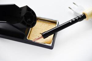 Soldering iron with a wooden handle in the holder. A soldering iron stand. photo