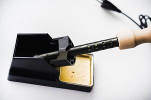 Soldering iron with a wooden handle in the holder. A soldering iron stand. photo