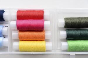 Multicolored skeins of thread in the set. The threads are in a plastic box. photo