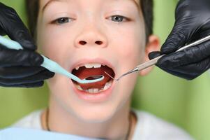 linda chico sonriente mientras dientes examen . contento chico sentado en dentistas silla y teniendo cheque arriba dientes foto