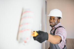 African-American decorator painting light wall photo