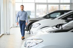 Concept of buying electric vehicle. Handsome business man stands near electric car at dealership photo