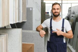Plumber in uniform at showcase in plumbering store photo
