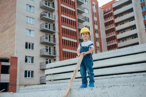 arquitecto en casco escritura alguna cosa cerca nuevo edificio. pequeño linda chico en el edificio como un arquitecto. foto