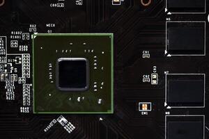 A brown printed circuit board with a processor chip and memory strips. Electronic components on the graphics card. photo