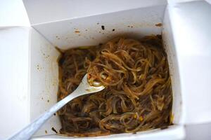 coreano tallarines con carne y salsa. udon tallarines en un cartulina caja. foto