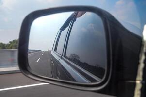 rearview mirror view of a car traveling at high speed on a toll road photo