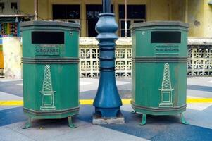 two green trash cans on the pedestrian or pathway or sidewalk photo