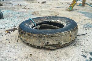a used car tire that is damaged and unused on the beach photo