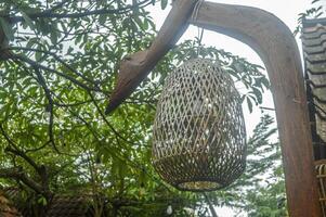 a wooden lantern with a led light in it hangs between the trees photo