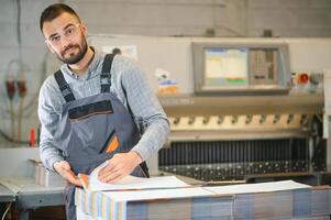 Man working in printing house with paper and paints photo