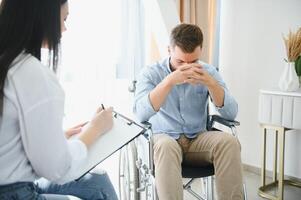 Young bearded man on wheelchair during home psychotherapy photo