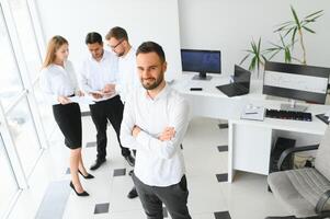 retrato de joven hermoso empresario en oficina con colegas en el antecedentes foto