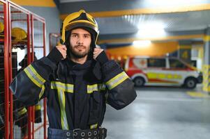 Fireman wearing protective uniform standing in fire department at fire station photo