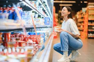 Happy young woman looking at product at grocery store. Smiling woman shopping in supermarket photo