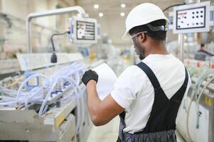 Professional Heavy Industry Engineer Worker Wearing Uniform, Glasses and Hard Hat in a Factory photo