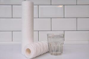 Water filters. Carbon cartridges and a glass on a white background. Household filtration system photo