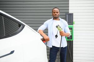 hombre cargando su eléctrico coche a cargar estación foto